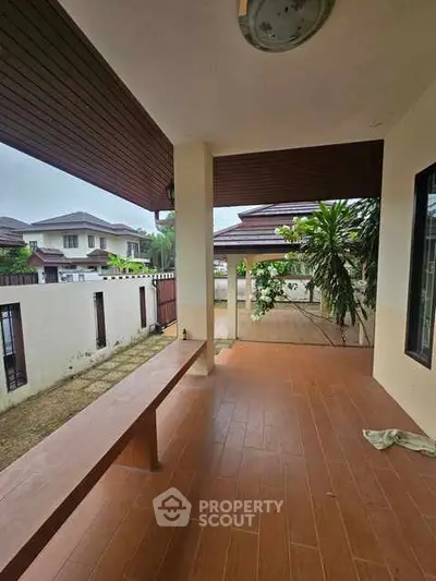 Charming covered patio with wooden ceiling and tiled flooring in suburban home.