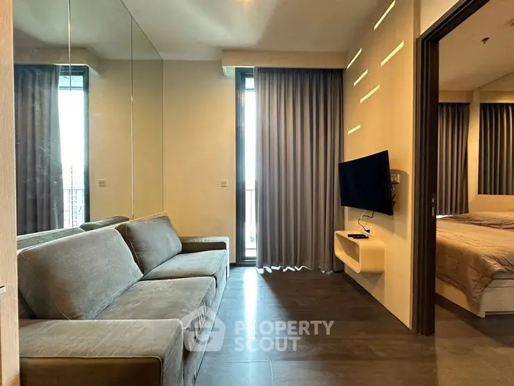 Modern living room with sleek design and cozy ambiance, featuring a wall-mounted TV and large mirror.