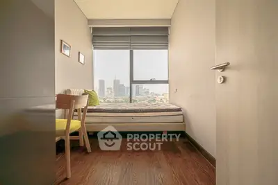 Cozy bedroom with city view, featuring wooden flooring and modern decor, perfect for urban living.