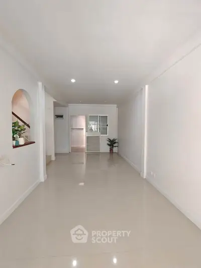 Spacious and bright interior with sleek white walls and glossy tiled flooring, perfect for modern living.