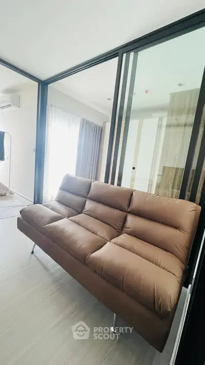 Modern living room with sleek brown sofa and glass sliding doors
