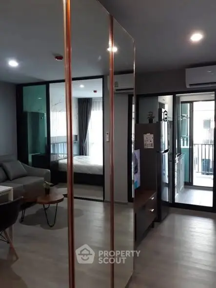 Modern apartment interior with open layout, featuring living room and kitchen with balcony view.