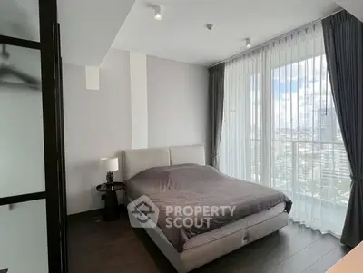 Modern bedroom with large windows and city view, featuring sleek design and natural light.