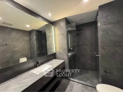 Luxurious modern bathroom with sleek gray tiles and glass shower enclosure