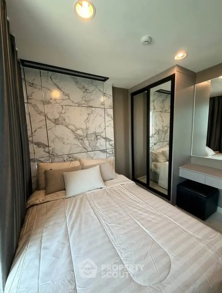 Luxurious bedroom with marble accent wall and mirrored wardrobe in modern apartment