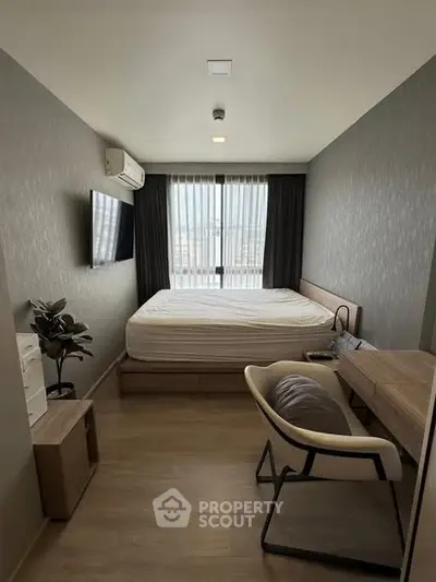 Modern bedroom with sleek furniture and large window offering natural light.