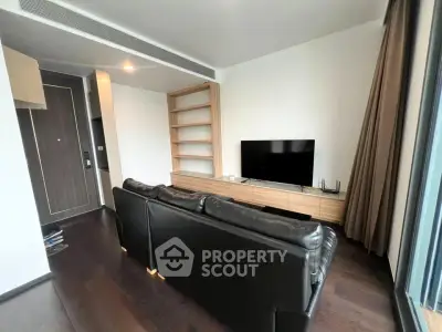 Modern living room with sleek black leather sofa and large TV, featuring elegant wooden shelving.