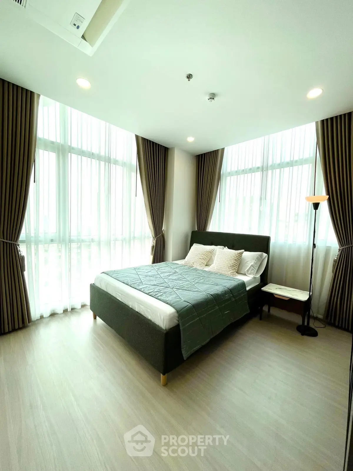 Spacious bedroom with large windows and elegant curtains in modern apartment