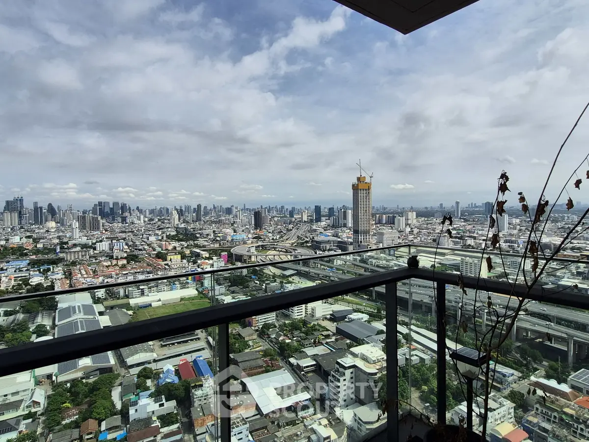 Stunning cityscape view from a high-rise balcony with glass railing, perfect for urban living.