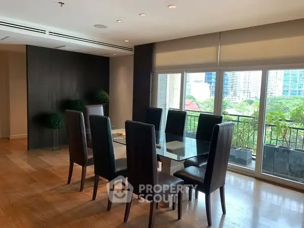 Spacious dining area with glass table and city view balcony in modern apartment.