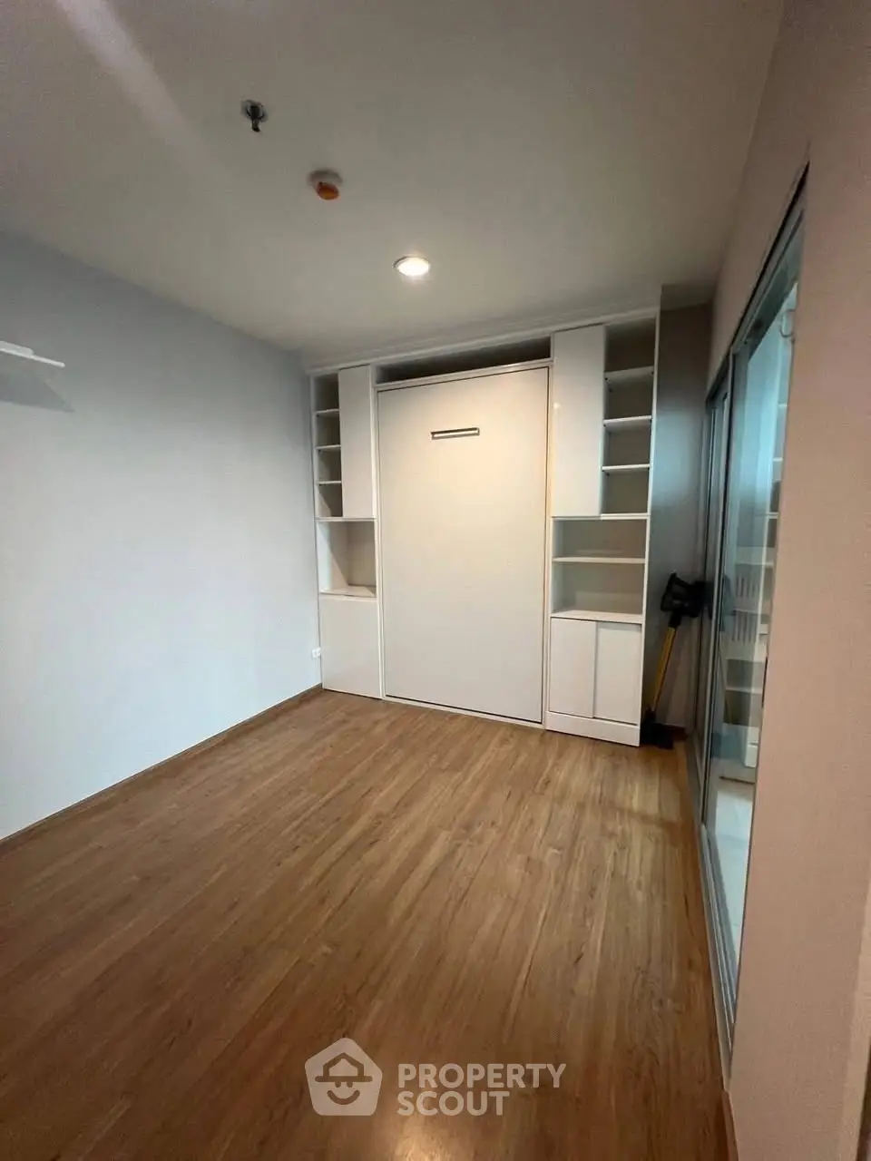 Modern room with built-in storage and Murphy bed, featuring sleek wooden flooring.