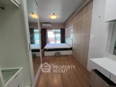 Modern bedroom with wooden flooring and mirrored wardrobe in a stylish apartment.