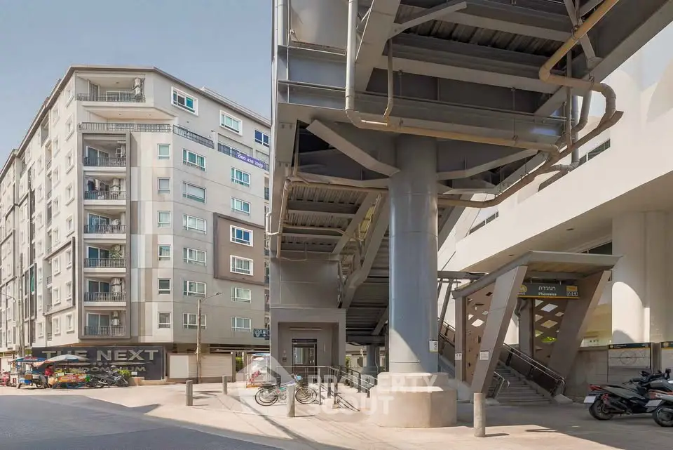 Modern urban building exterior with adjacent elevated walkway and street view.