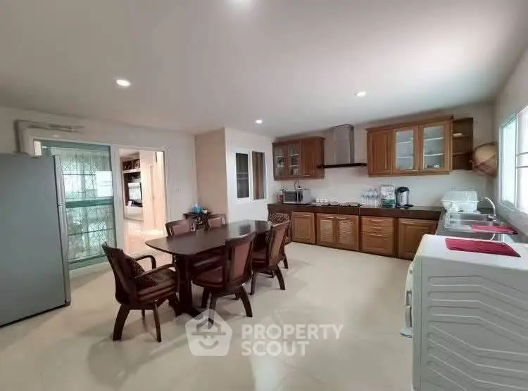 Spacious kitchen with dining area, wooden cabinets, and modern appliances in a bright, airy setting.