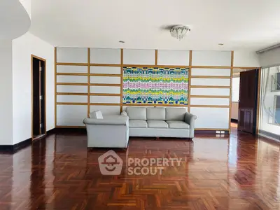 Spacious living room with elegant parquet flooring and modern sofa, featuring a vibrant wall art piece.