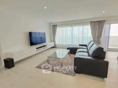 Spacious modern living room with sleek furniture and large windows.