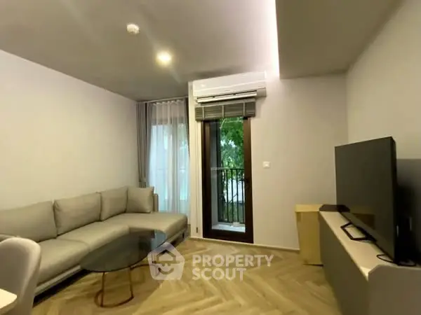 Modern living room with sleek design, featuring a cozy sofa, large TV, and balcony access.
