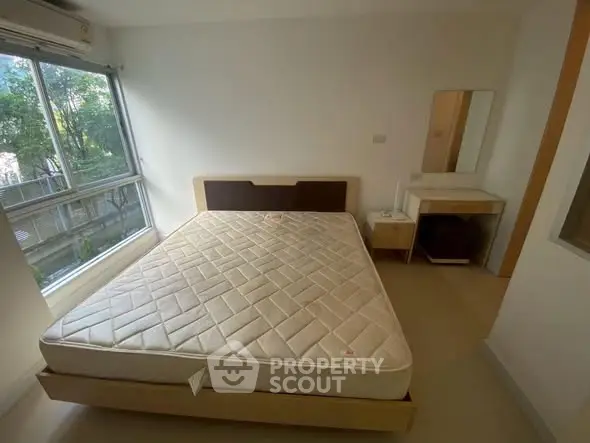 Spacious bedroom with large window and natural light in modern apartment