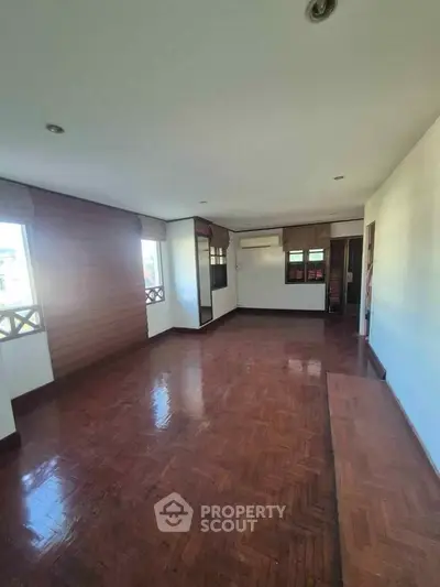 Spacious living room with wooden flooring and large windows for natural light.