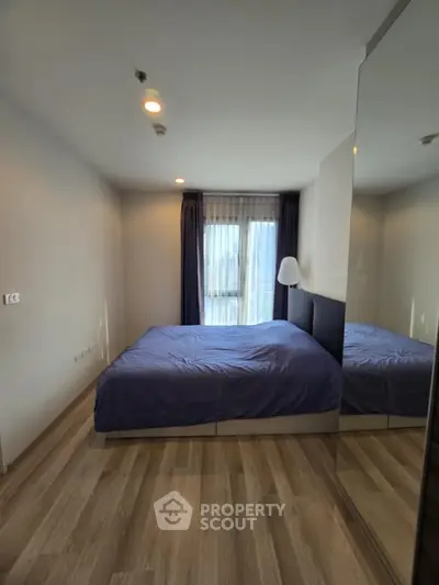 Modern bedroom with large mirror and cozy bed, perfect for relaxation.