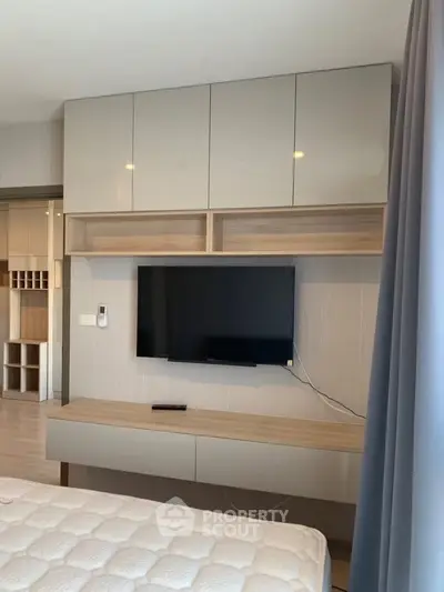 Modern bedroom with wall-mounted TV and sleek storage cabinets