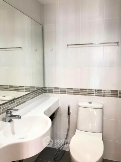 Modern bathroom with sleek fixtures and minimalist design, featuring a wall-mounted sink and toilet.