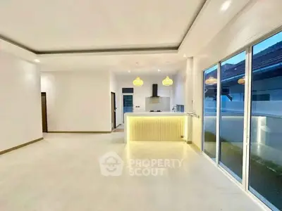 Spacious open-plan living room with modern kitchen and large sliding doors to balcony.