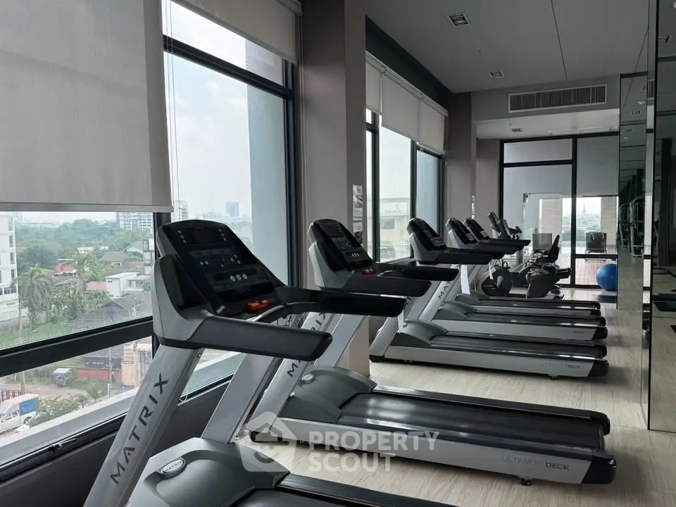 Modern gym with treadmills and large windows offering city views.