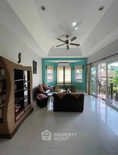 Spacious living room with modern decor and large windows opening to a lush garden view.