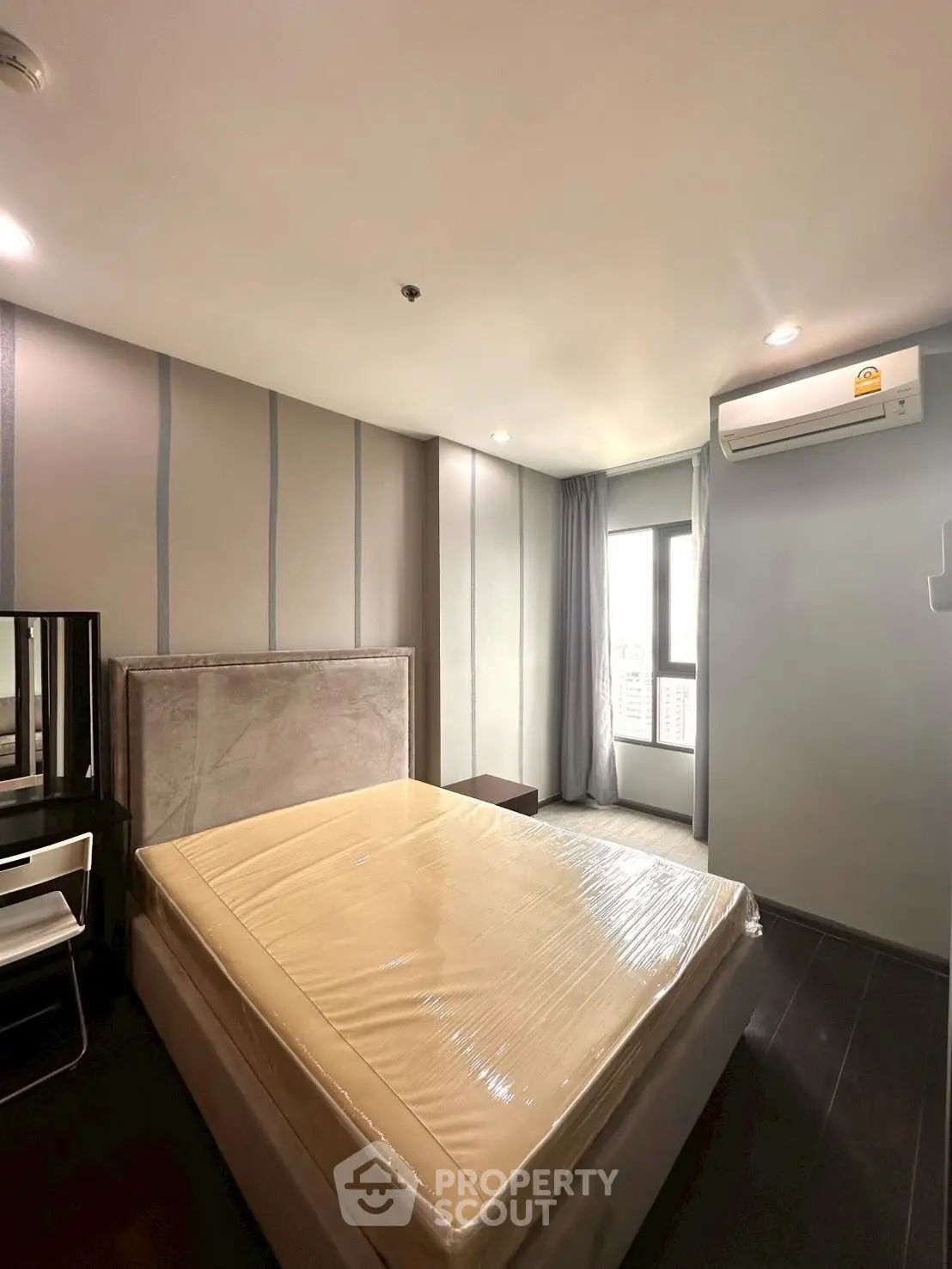 Modern bedroom with stylish decor and natural light, featuring a comfortable bed and air conditioning.