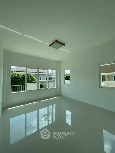 Spacious empty room with large windows and glossy tiled floor, perfect for customization.