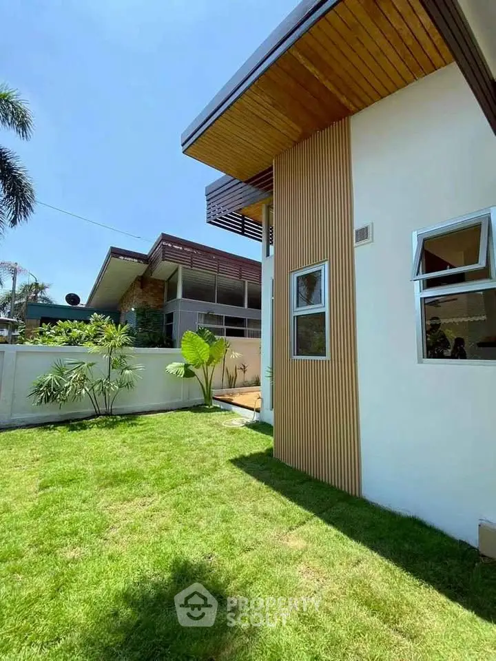 Modern architectural home exterior with lush green lawn and sleek design.