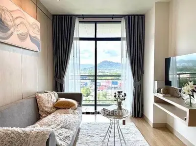 Chic living room with cozy sofa and stunning mountain view through large window.