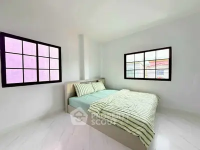 Bright minimalist bedroom with large windows and modern bed setup.