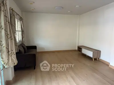 Spacious living room with wooden flooring and minimalist furniture, perfect for modern living.