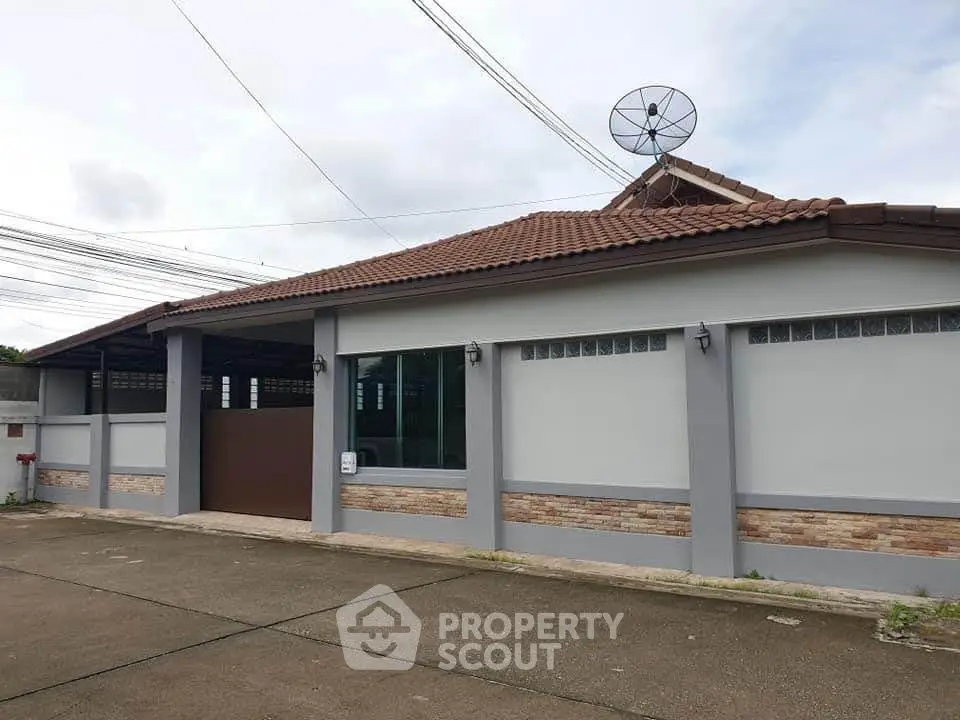 Charming single-story home with tiled roof and satellite dish, offering privacy and modern amenities.