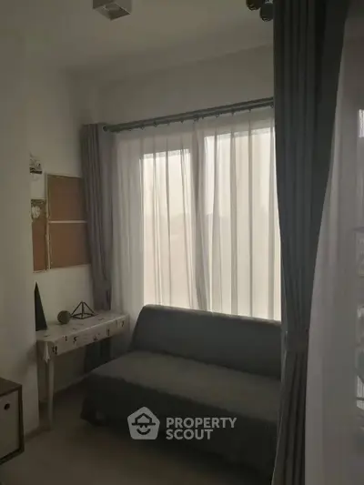 Cozy small living room with a sofa and sheer curtains, perfect for relaxation.