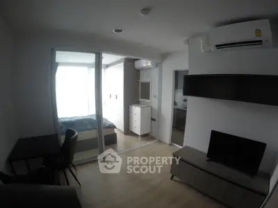 Modern compact apartment with bedroom and living area, featuring sleek furniture and air conditioning.