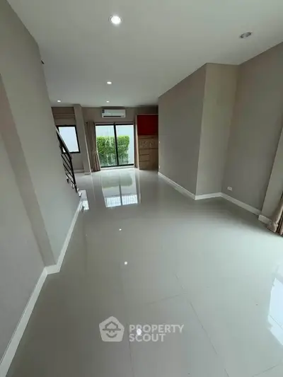 Spacious modern living room with glossy tile flooring and large windows for natural light.