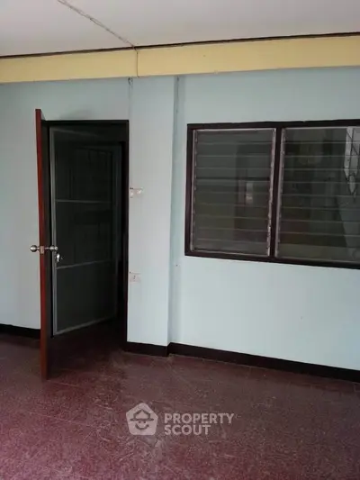 Simple interior room with open door and window, showcasing basic design.