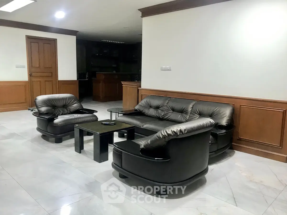 Spacious living room with elegant leather furniture and wooden accents, perfect for relaxation and entertainment.