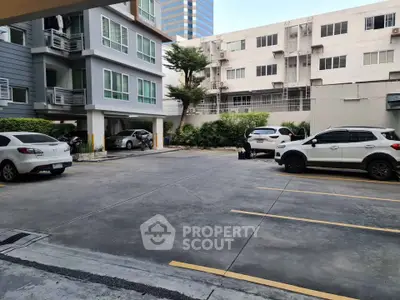 Spacious parking area in modern residential complex with multiple parking spaces and surrounding greenery.