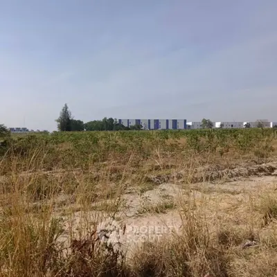Expansive land plot with distant modern buildings under clear sky