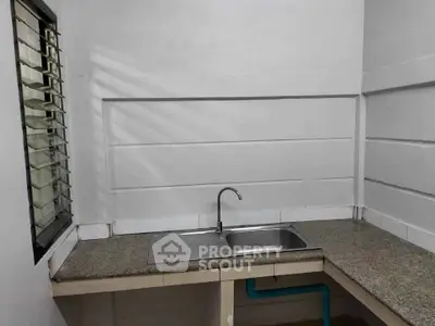 Compact kitchen with granite countertop and single sink, featuring a side window for natural light.