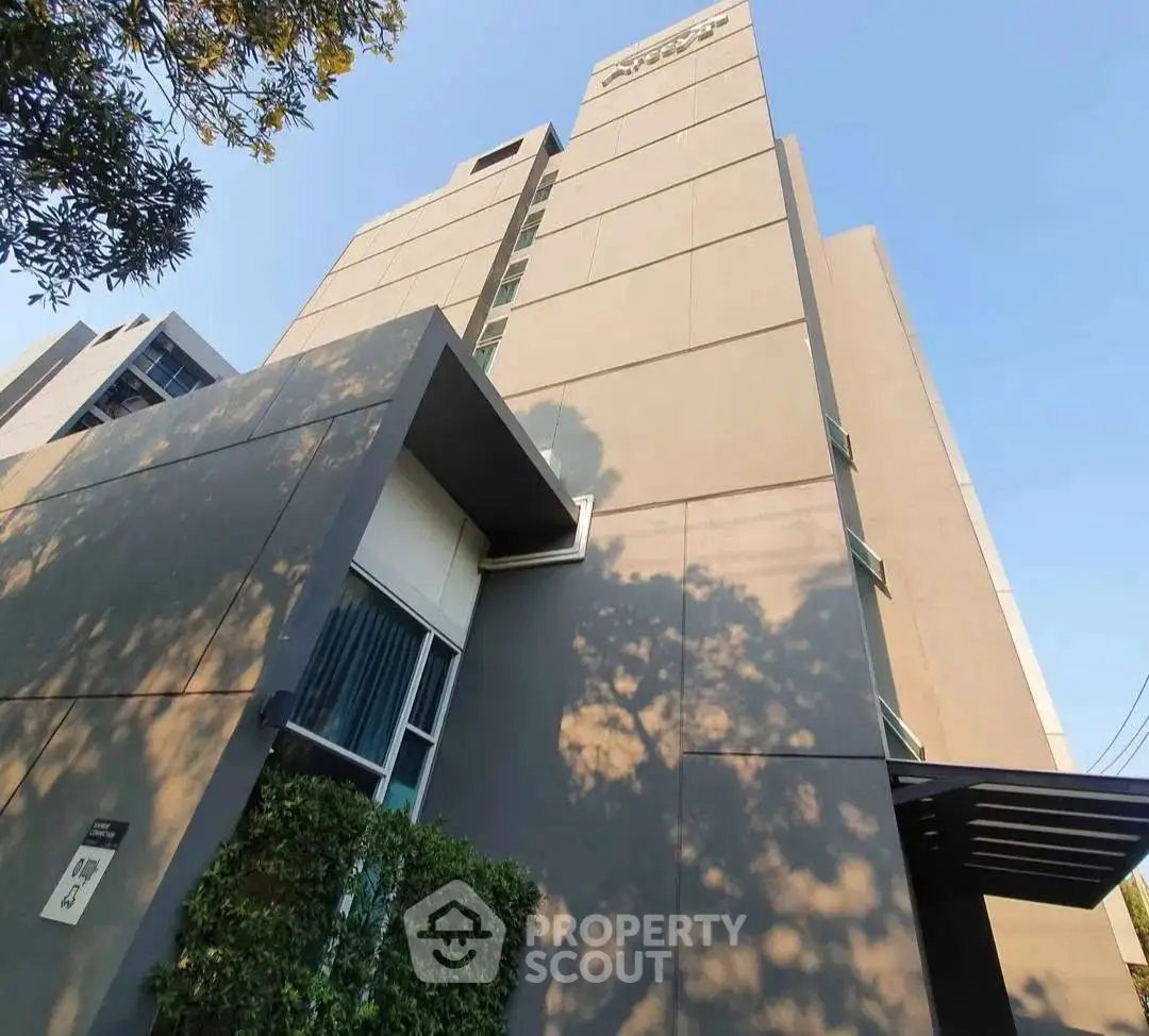 Modern urban building exterior with sleek design and lush greenery, perfect for city living.