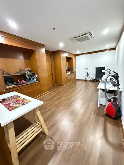 Spacious study room with wooden flooring and built-in shelves, perfect for creative projects.