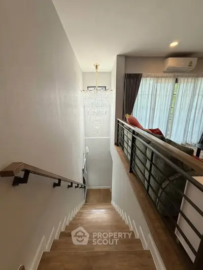 Elegant staircase with chandelier and modern living room view