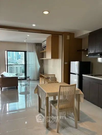 Modern open-plan living room with kitchen and city view, featuring sleek furniture and natural light.
