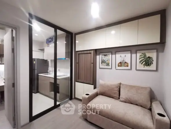 Modern living room with cozy sofa and glass partitioned kitchen in a stylish apartment.