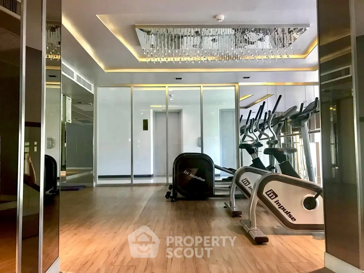 Luxurious gym with modern equipment and elegant lighting in upscale residential building.